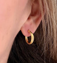 Load image into Gallery viewer, gold cross over hoop earrings in a model's ear