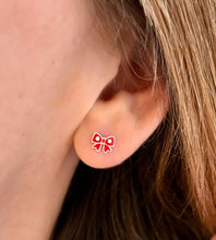 Load image into Gallery viewer, Close-up of an ear wearing a sterling silver Christmas red bow earring.