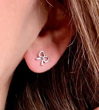 Load image into Gallery viewer, Silver bow-shaped earring worn by a person with brown hair.