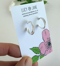 Load image into Gallery viewer, sterling silver double crossover hoop earrings on a lucy and jane earring card
