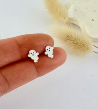 Load image into Gallery viewer, Small ghost-shaped earrings held between fingers with a light background