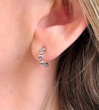Load image into Gallery viewer, sterling silver skull hoop earrings in model's ear. Hoop earrings featuring lots of small skulls. Great for Halloween's or earrings for goths