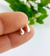 Load image into Gallery viewer, tiny sterling silver teardrop earrings on a person's finger with a blurred green leaf background