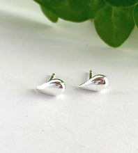 Load image into Gallery viewer, small sterling silver teardrop earrings on a white surface with green leaves in the background