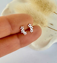 Load image into Gallery viewer, sterling silver 3 star mini climber earrings held between fingers