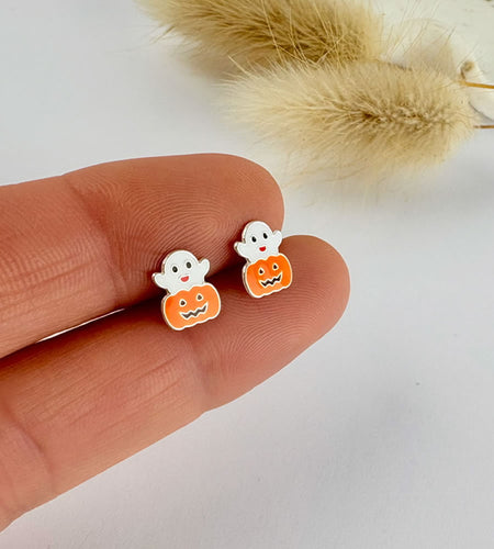 Sterling silver Halloween-themed ghost and pumpkin earrings on a finger with a neutral background