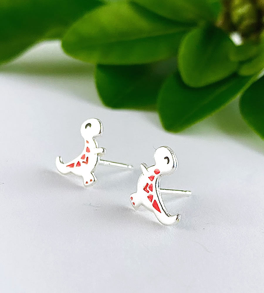 sterling silver t rex dinsoaur studs with a little pop of orange detailing on their backs