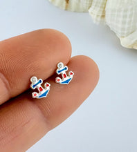 Load image into Gallery viewer, Sterling silver red, white an blue Anchor-shaped earrings held between fingers with a shell in the background