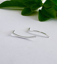 Load image into Gallery viewer, Sterling silver curved earrings on a white surface with green leaves in the background