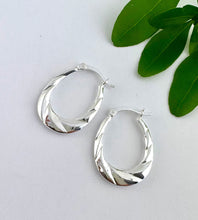Load image into Gallery viewer, sterling silver oval hoops with a diamond cut / twist effect.  Lever fixing to make them easy to wear.
