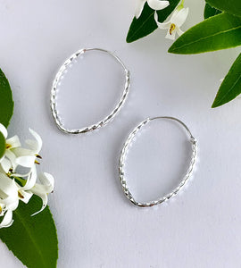 sterling silver teardrop shaped hoops on a plain white background