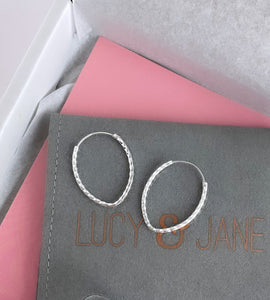 sterling silver diamond cut teardrop hoops on a grey jewellery pouch 