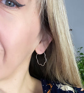 sterling silver flower shaped hoop earring through model's ear
