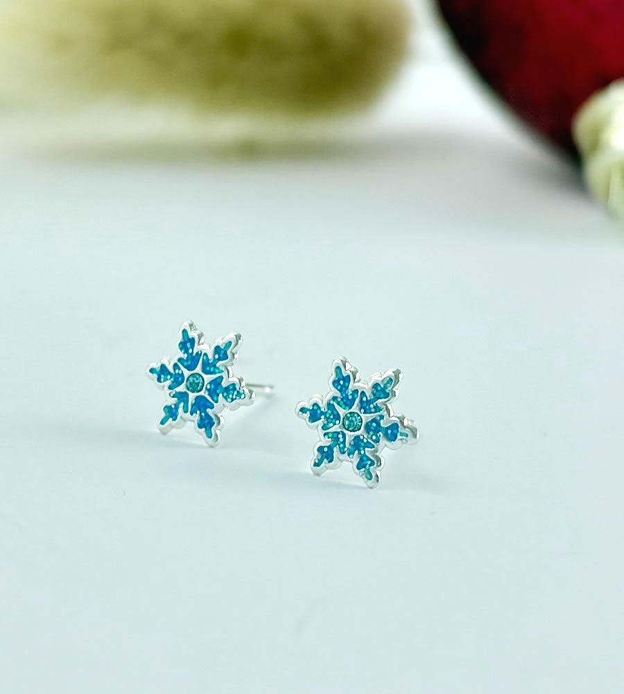 Pair of sterling silver blue snowflake earrings on a light gray background