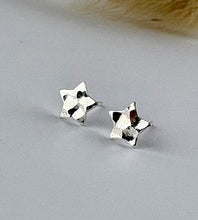 Load image into Gallery viewer, sterling silver star studs that are hammered to catch the light.  Displayed on a plain white background.
