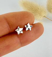 Load image into Gallery viewer, sterling silver hammered star studs held between fingers