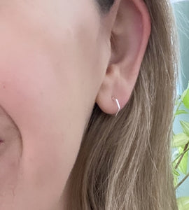 sterling silver hexagon huggie half hoops on a model's ear