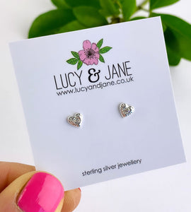 small sterling silver heart earrings that are textured with a small clear crystal in the middle of the heart earrings.  The earrings are on a white backing card.