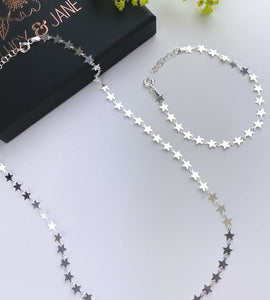 Sterling silver multi stars necklace next to a matching silver stars bracelet 